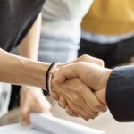 Dos manos de dos personas saludandose en señal de trato hecho.