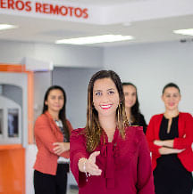 Imagen de cuatro funcionarias del Banco Popular en una oficina comercial sonriendo hacia la cámara ofreciendo su mano hacia el cliente.