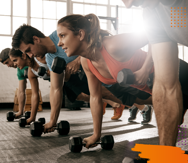 Grupo de personas en un gimnasio haciendo ejercicios mientras sonrien.