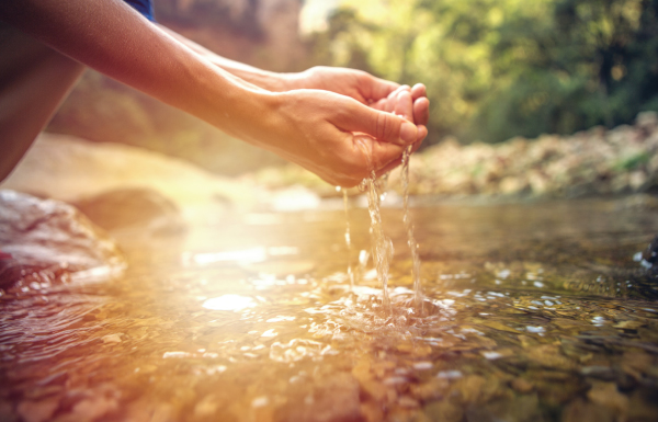imagen de manos tomando agua de un río