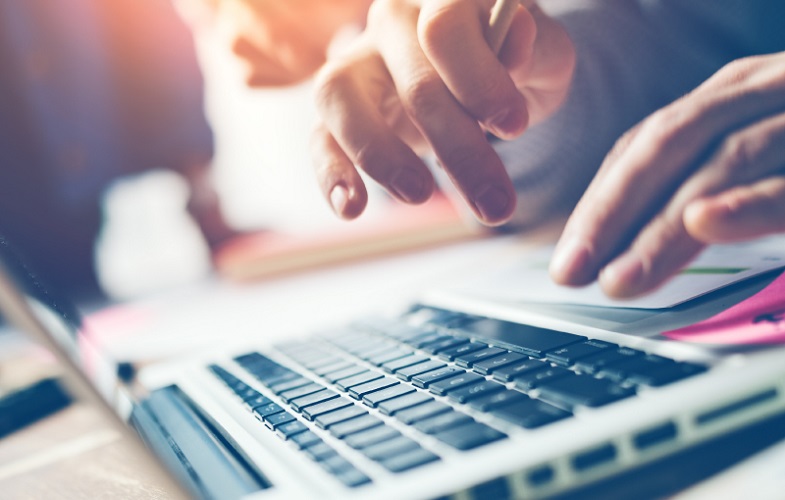 Manos digitando sobre teclado de laptop.