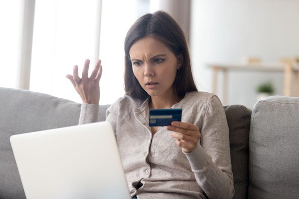 Mujer con laptop y tarjeta en la mano, confundida