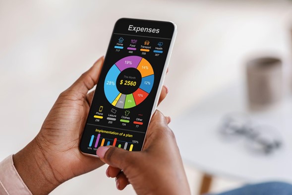 unas manos sosteniendo un celular, que muestra una aplicación con gráficos de finanzas.