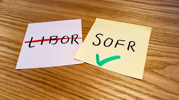 sobre una mesa de madera, 2 post it donde en uno se muestras la palabra escrita Libor con una raya roja encima y en otra la palabra SOFR con un check verde.