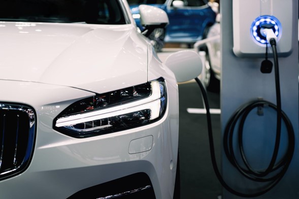 un carro eléctrico color blanco, conectado a un cargador de vehīculo