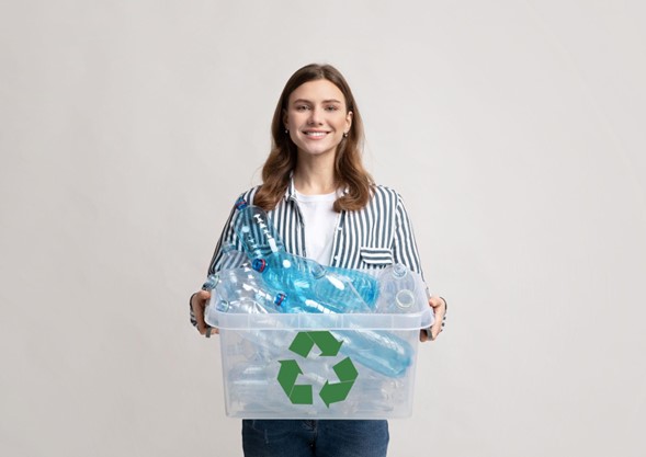 Mujer sosteniendo una canasta plástica con el símbolo de reciclaje, llena de botellas plásticas.