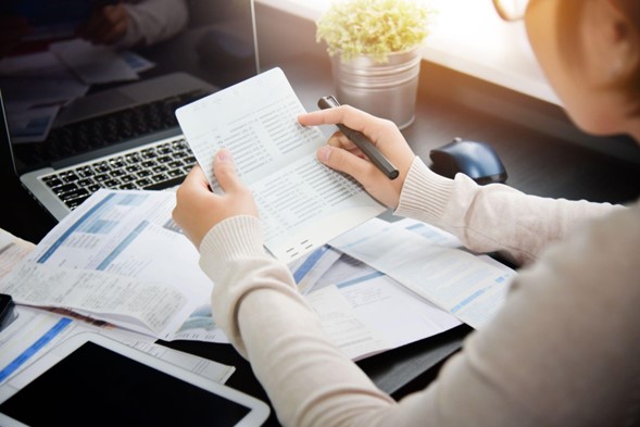 Mujer revisando documentos que tiene en las manos.