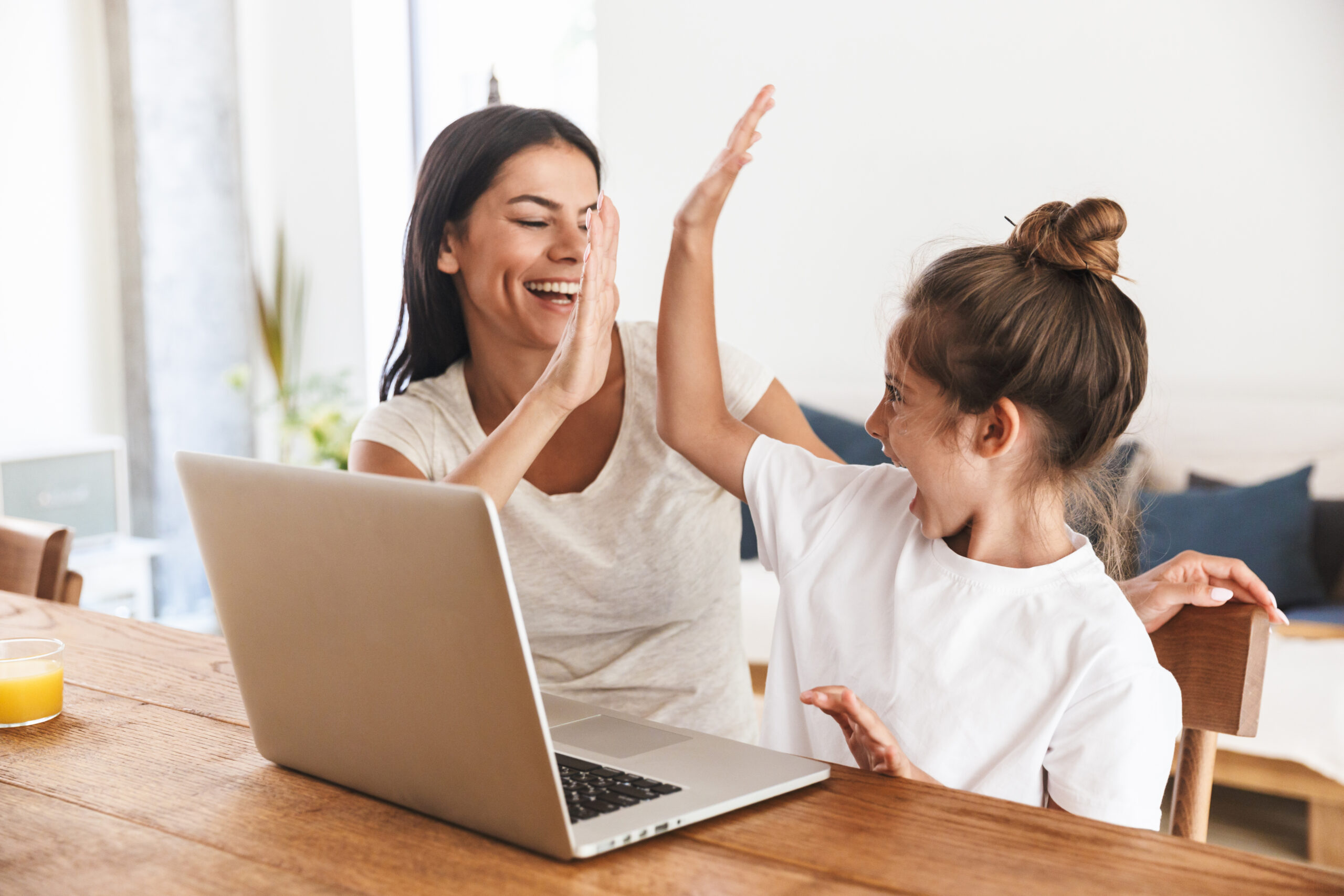 mujer y niña sentadas en la mesa con una computadora