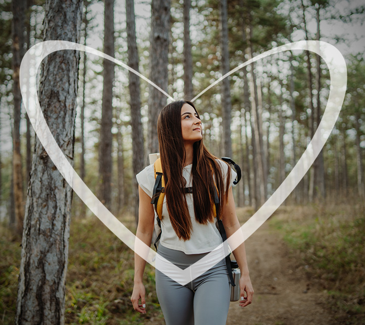Mujer joven haciendo senderismo en el bosque, rodeada por un corazón transparente