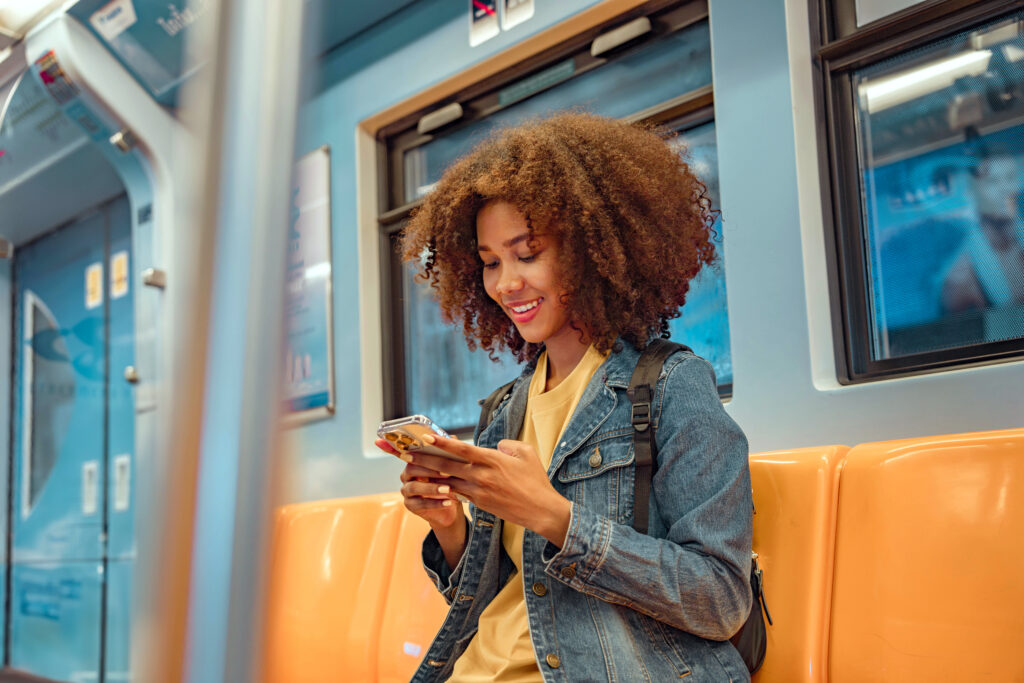 mujer sentada en el asiendo del tren con un teléfono celular en sus manos