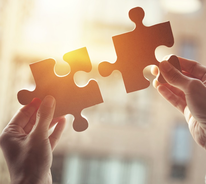 Businesswoman hand connecting jigsaw puzzle with sunlight effect