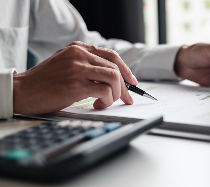 Focused businessman checking reports and verifying office documents with calculator and paper files on table