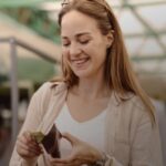 Persona en un mercado sosteniendo una billetera con billetes, junto a una canasta llena de frutas y verduras frescas. Imagen representa compras presenciales y pago en efectivo
