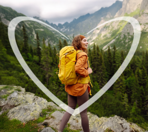 Una mujer joven con jacket naranja mira el paisaje desde la cima de una montaña en turismo.