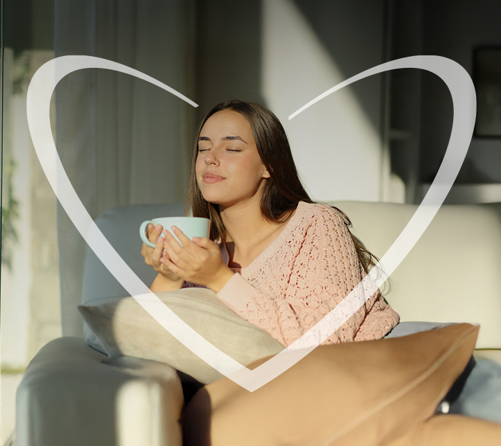 Mujer feliz sentada en el sillón de su sala mientras toma un té con el estrés bajo control