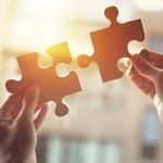 Businesswoman hand connecting jigsaw puzzle with sunlight effect