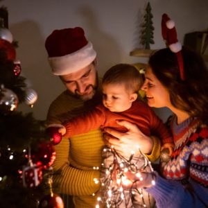 Padres y bebe disfrutando de las luces y adornos del arbol de Navidad - copia