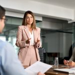Busy mature professional board executive colleagues successful business team people collaborating having corporate teamwork discussion together at group office conference meeting boardroom table.