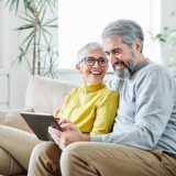 portrait of happy smiling senior couple using tablet at home