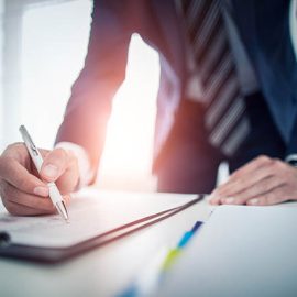 Business man signing contract document on office desk, making a deal.