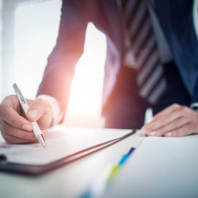 Business man signing contract document on office desk, making a deal.