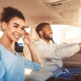 Road Trip. Happy Black Couple Driving Sitting In Car Travelling On Summer Vacation. Selective Focus